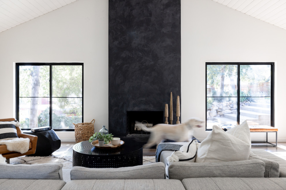 Стильный дизайн: гостиная комната в скандинавском стиле с светлым паркетным полом, стандартным камином и фасадом камина из штукатурки - последний тренд