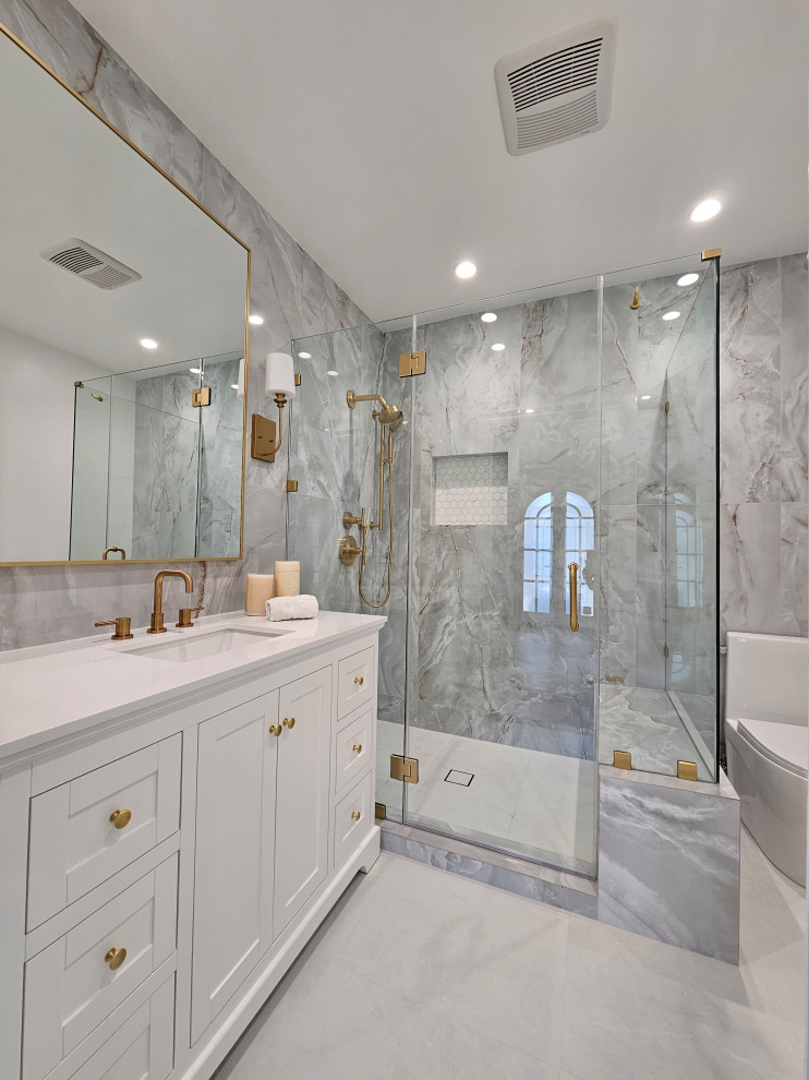 Inspiration for a medium sized traditional bathroom in Los Angeles with shaker cabinets, white cabinets, a one-piece toilet, grey tiles, porcelain tiles, porcelain flooring, a submerged sink, marble worktops, grey floors, a hinged door, white worktops, a single sink and a freestanding vanity unit.