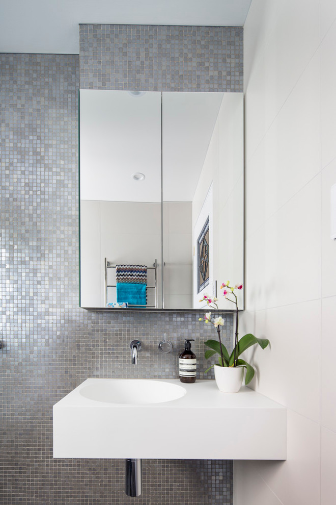 Photo of a small scandinavian bathroom in Brisbane with a wall-mount sink, solid surface benchtops, an open shower, a one-piece toilet, gray tile, mosaic tile, white walls, porcelain floors and grey floor.