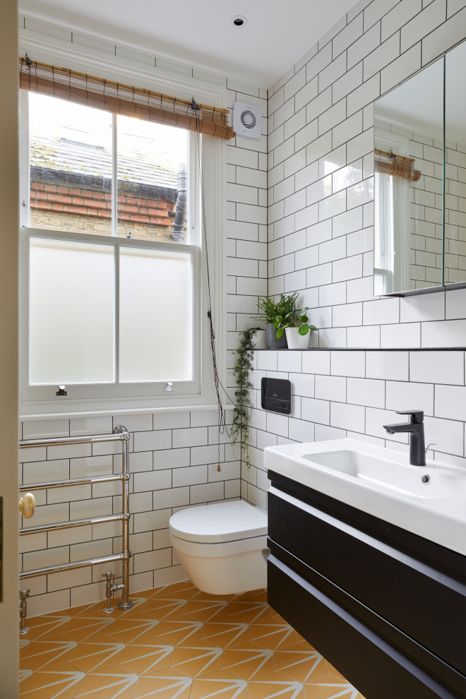 Immagine di una stanza da bagno per bambini classica con vasca da incasso, WC sospeso, pareti gialle, pavimento con piastrelle in ceramica, lavabo integrato, pavimento rosa, nicchia e mobile bagno sospeso