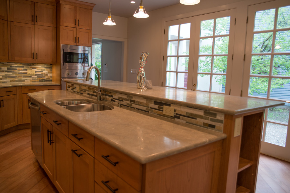Example of a large transitional l-shaped medium tone wood floor eat-in kitchen design with a double-bowl sink, recessed-panel cabinets, medium tone wood cabinets, concrete countertops, multicolored backsplash, matchstick tile backsplash, stainless steel appliances and an island