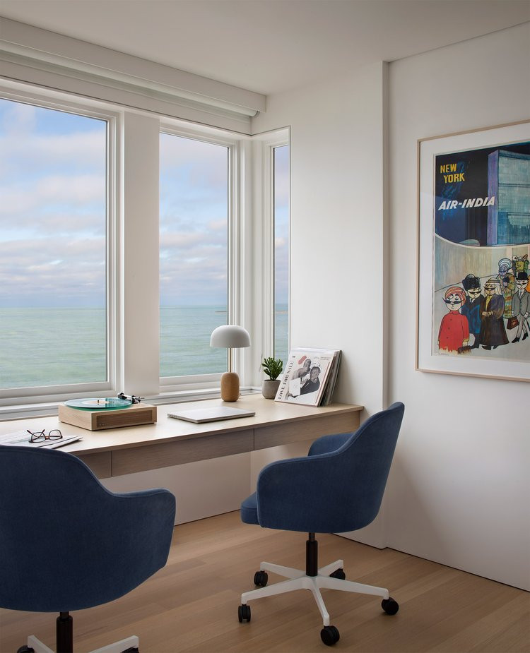 This is an example of a medium sized modern study in Chicago with white walls, light hardwood flooring, a built-in desk and beige floors.