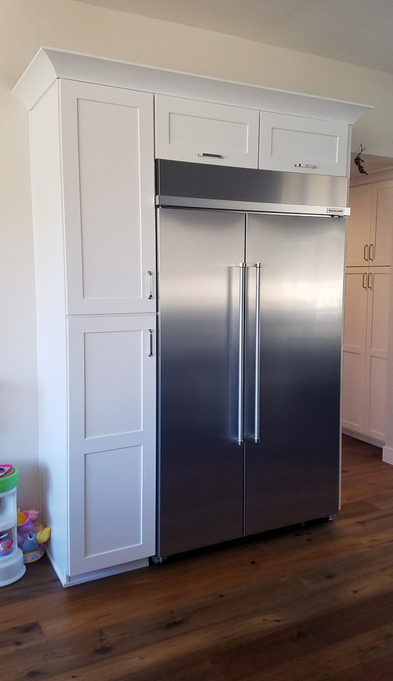 Inspiration for a large transitional l-shaped medium tone wood floor eat-in kitchen remodel in Phoenix with an undermount sink, shaker cabinets, white cabinets, granite countertops, gray backsplash, subway tile backsplash, stainless steel appliances and an island
