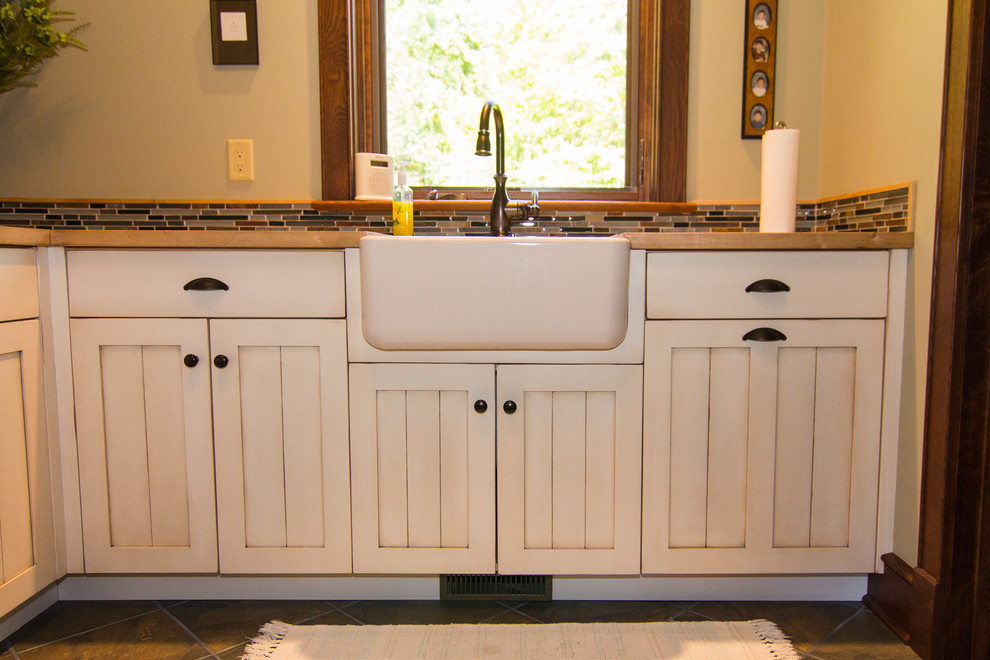 Inspiration for a large country laundry room in Other with a farmhouse sink, recessed-panel cabinets, distressed cabinets, wood benchtops, beige walls and a side-by-side washer and dryer.