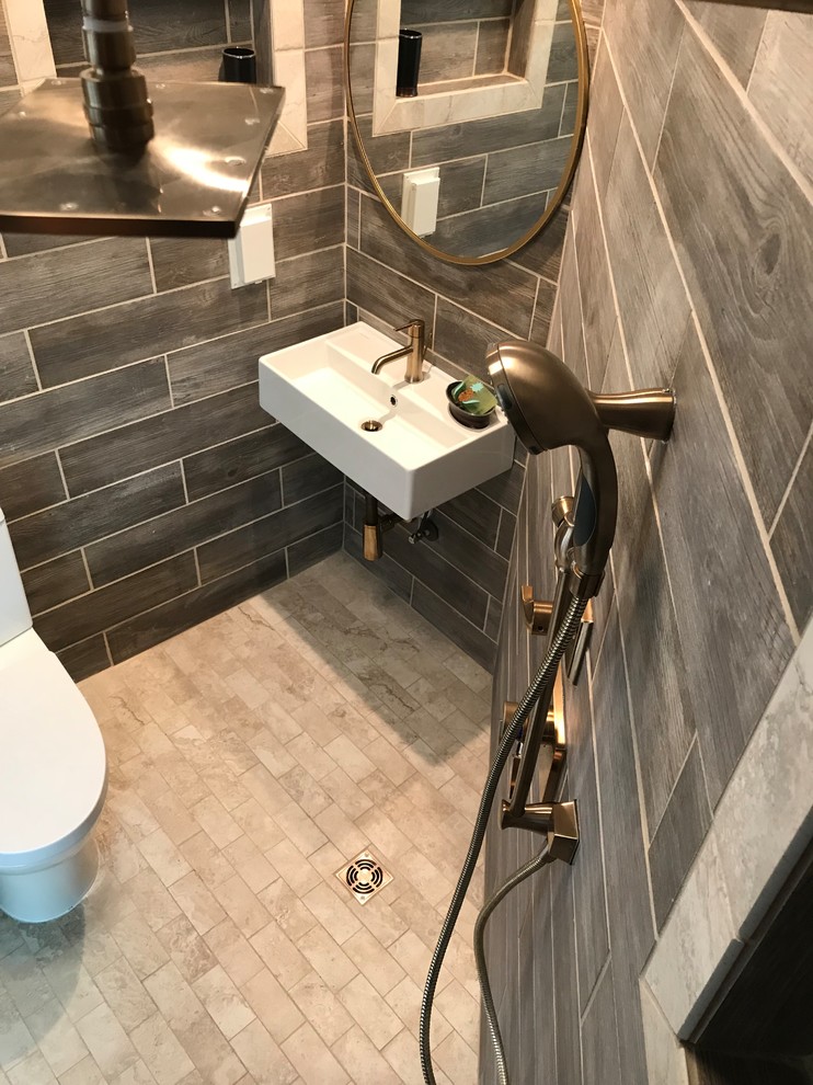 Photo of a small modern master wet room bathroom in Other with a two-piece toilet, brown tile, ceramic tile, brown walls, ceramic floors, a wall-mount sink, beige floor and a hinged shower door.