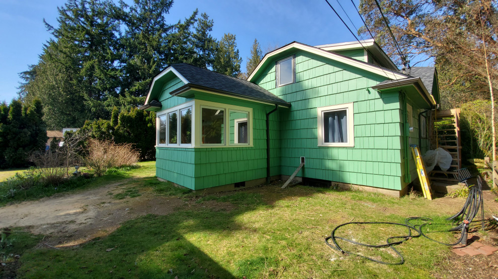 This is an example of a small arts and crafts two-storey green house exterior in Seattle with wood siding, a clipped gable roof, a shingle roof, a grey roof and shingle siding.