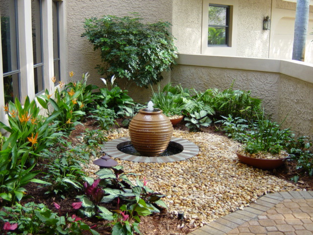 Photo of a small tropical front yard partial sun garden in Miami with a water feature and gravel.