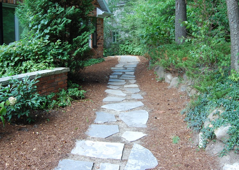 Photo of a mid-sized traditional side yard partial sun garden for spring in Toronto with a garden path and natural stone pavers.