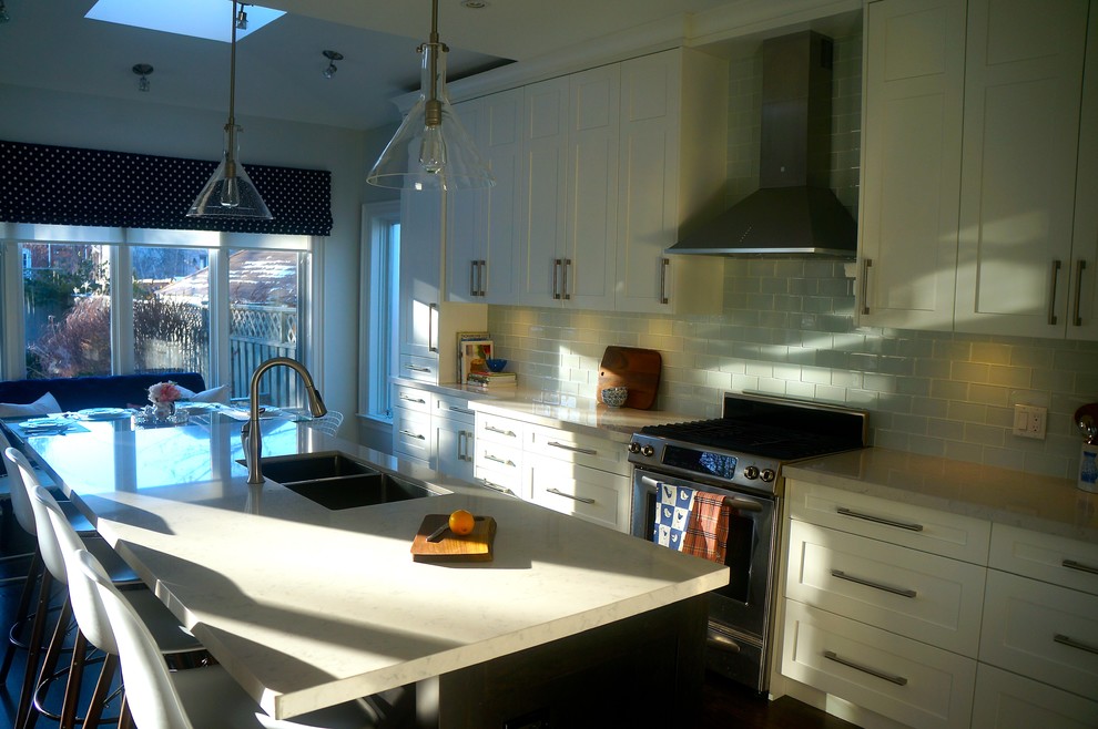 Example of a transitional galley dark wood floor kitchen design in Toronto with an undermount sink, shaker cabinets, white cabinets, quartz countertops, blue backsplash, glass tile backsplash, stainless steel appliances and an island
