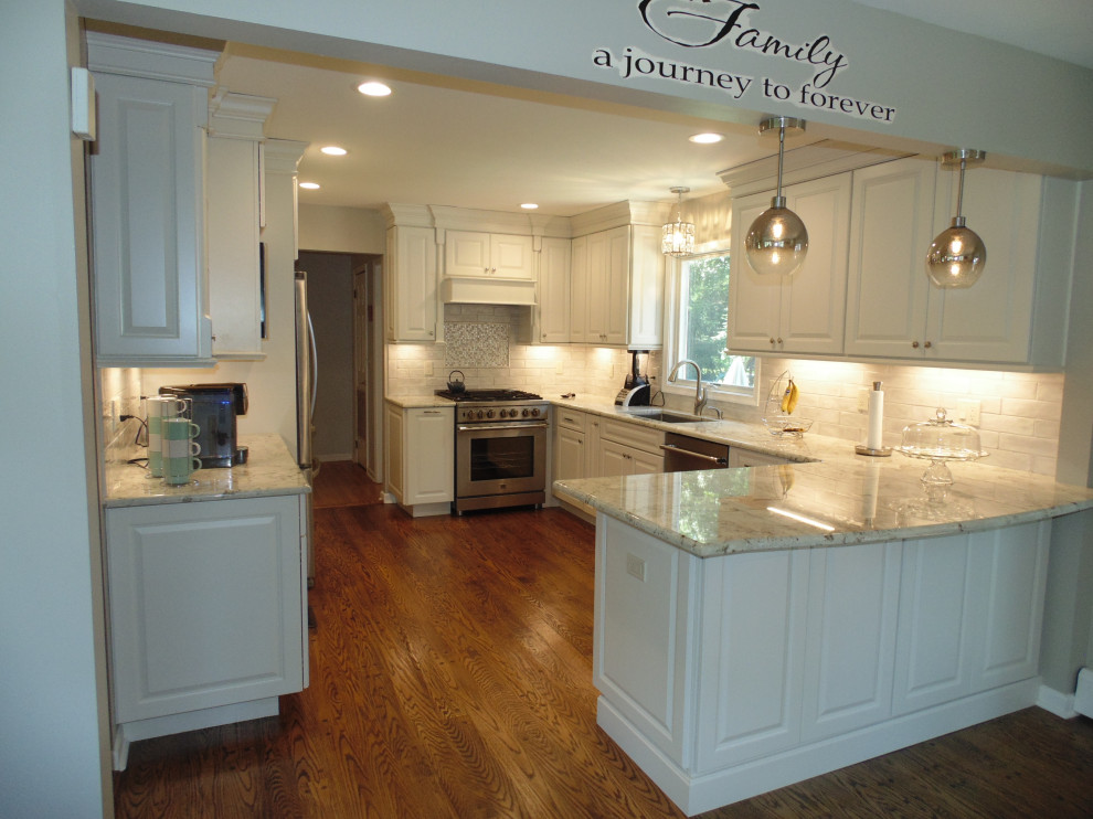 Inspiration for a mid-sized transitional u-shaped medium tone wood floor and brown floor eat-in kitchen remodel with an undermount sink, raised-panel cabinets, white cabinets, granite countertops, white backsplash, subway tile backsplash, stainless steel appliances, no island and gray countertops