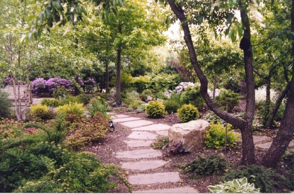 This is an example of a traditional sloped garden in New York with a garden path and natural stone pavers.