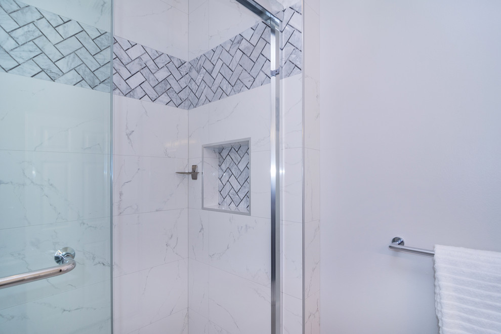 This is an example of a mid-sized contemporary kids bathroom in Miami with shaker cabinets, white cabinets, a drop-in tub, a one-piece toilet, gray tile, porcelain tile, grey walls, porcelain floors, an undermount sink, solid surface benchtops, grey floor, a sliding shower screen and white benchtops.
