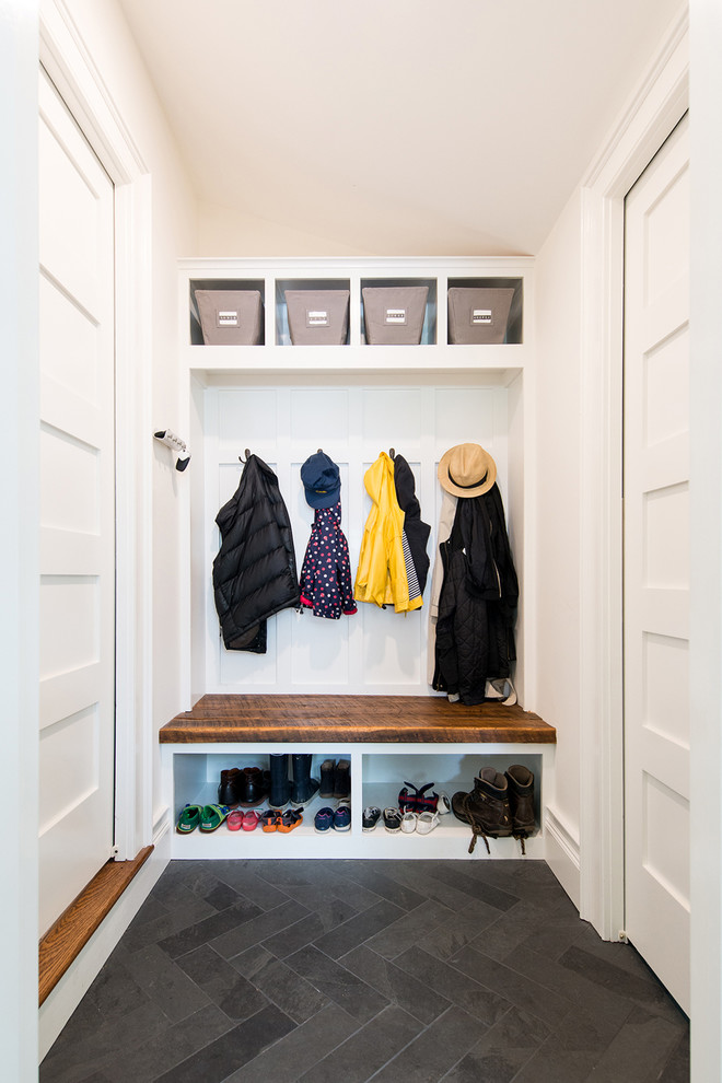 This is an example of a small transitional mudroom in DC Metro with white walls, slate floors, a white front door and black floor.