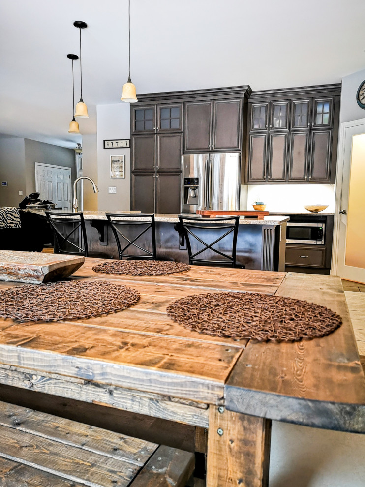 Example of a mid-sized mountain style l-shaped medium tone wood floor and brown floor eat-in kitchen design with a double-bowl sink, recessed-panel cabinets, dark wood cabinets, granite countertops, stainless steel appliances, an island and gray countertops