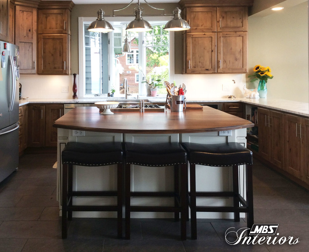 Mid-sized transitional u-shaped ceramic tile and gray floor eat-in kitchen photo with a farmhouse sink, recessed-panel cabinets, medium tone wood cabinets, marble countertops, white backsplash, subway tile backsplash, stainless steel appliances and an island