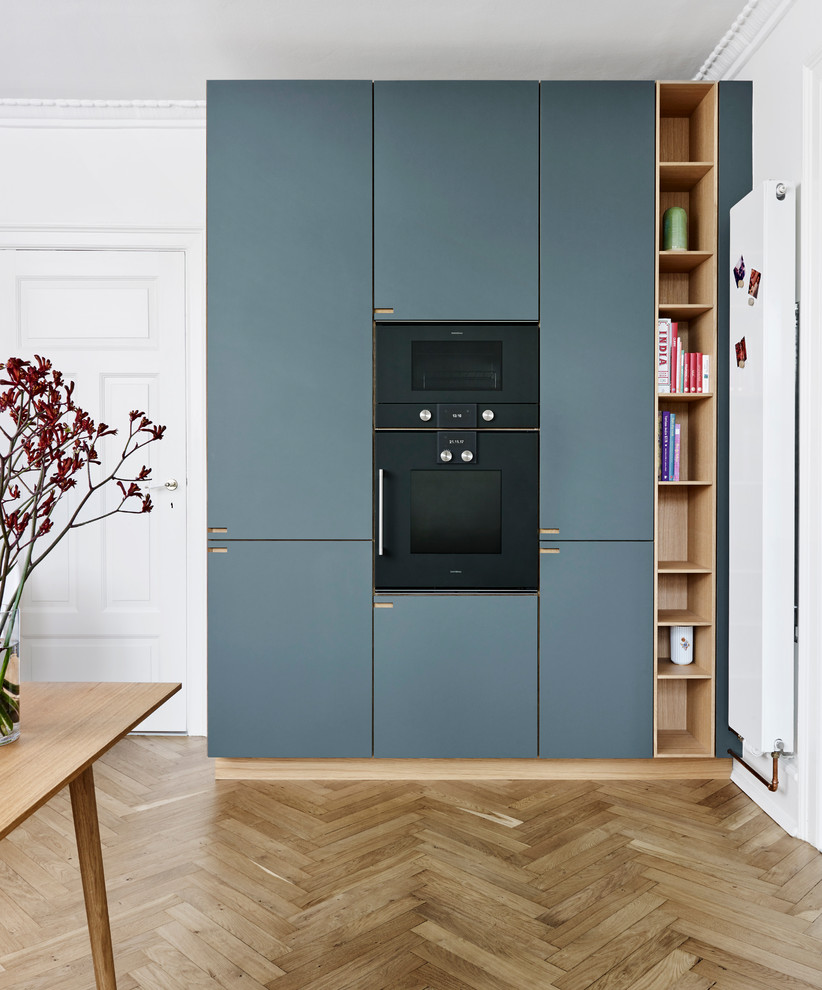 This is an example of a large scandinavian l-shaped eat-in kitchen in Copenhagen with a single-bowl sink, flat-panel cabinets, blue cabinets, brown splashback, timber splashback, coloured appliances, medium hardwood floors, with island and brown floor.