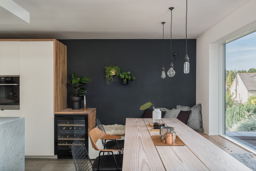 Immagine di una sala da pranzo aperta verso la cucina nordica di medie dimensioni con pareti nere, parquet chiaro e pavimento grigio
