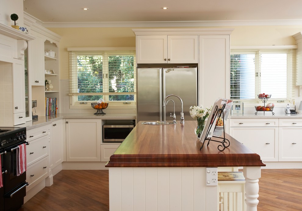 Design ideas for a large traditional u-shaped eat-in kitchen in Sydney with wood benchtops, a single-bowl sink, shaker cabinets, white cabinets, white splashback, ceramic splashback, stainless steel appliances, medium hardwood floors and with island.