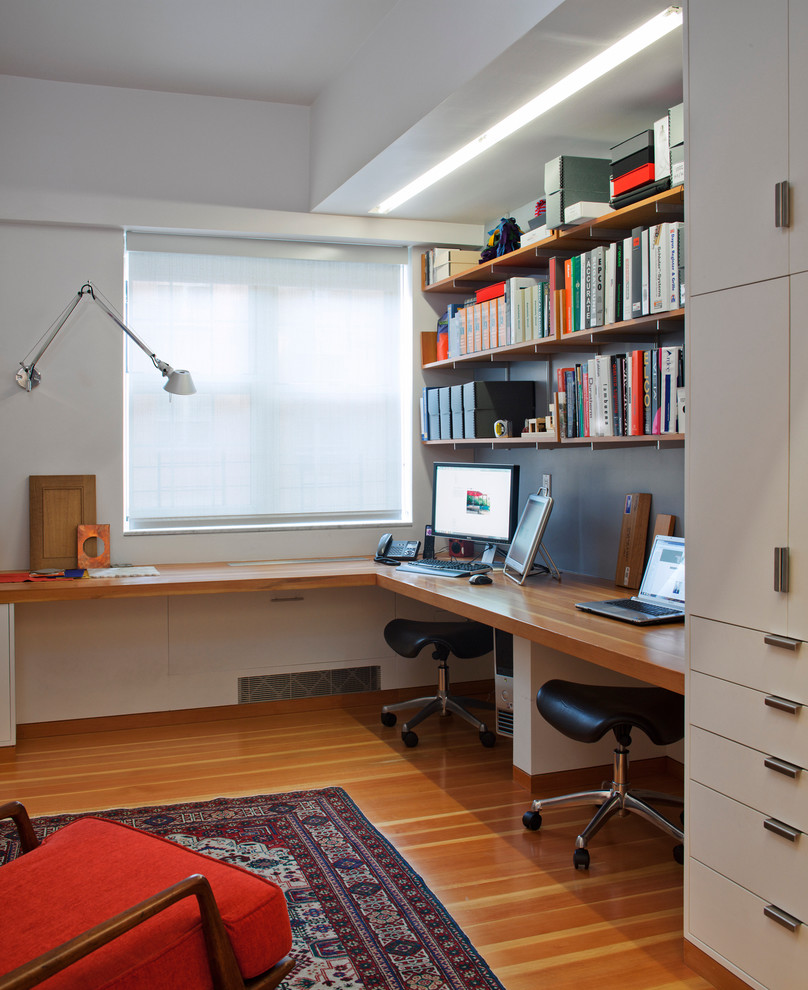 Design ideas for a contemporary home office in New York with white walls, medium hardwood floors and a built-in desk.