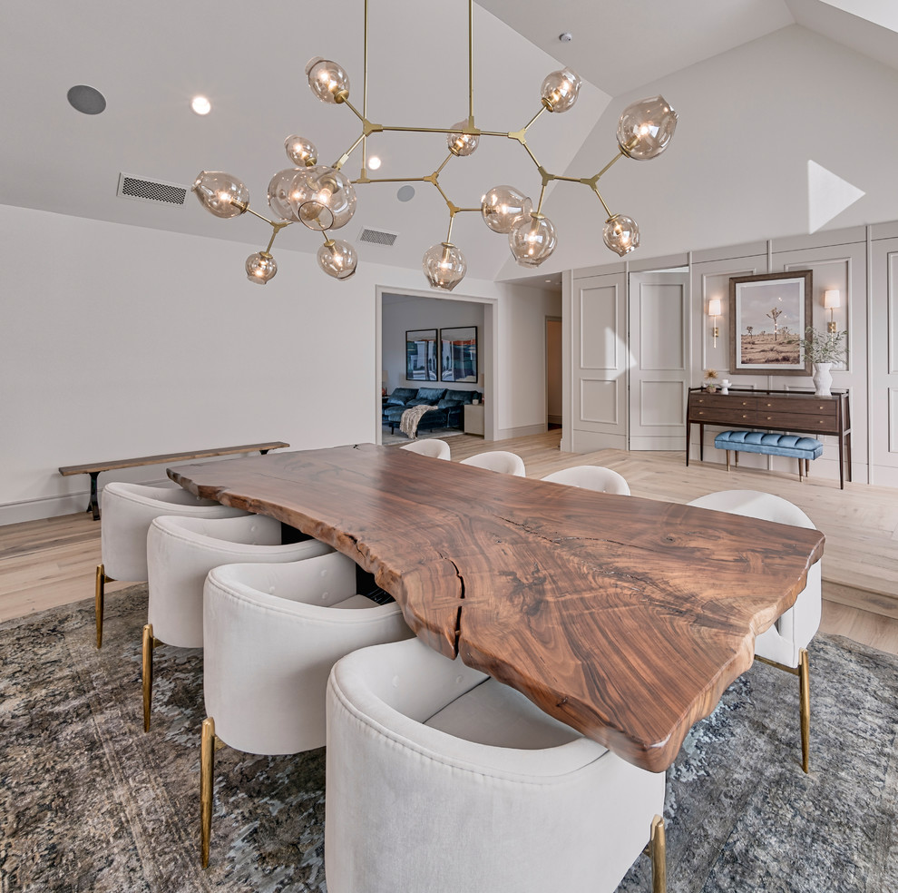 This is an example of a mid-sized contemporary open plan dining in Las Vegas with white walls, light hardwood floors, a standard fireplace and a plaster fireplace surround.