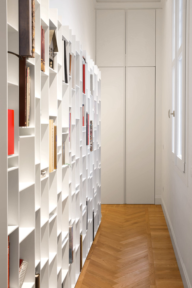 This is an example of a mid-sized contemporary hallway in Milan with white walls and medium hardwood floors.