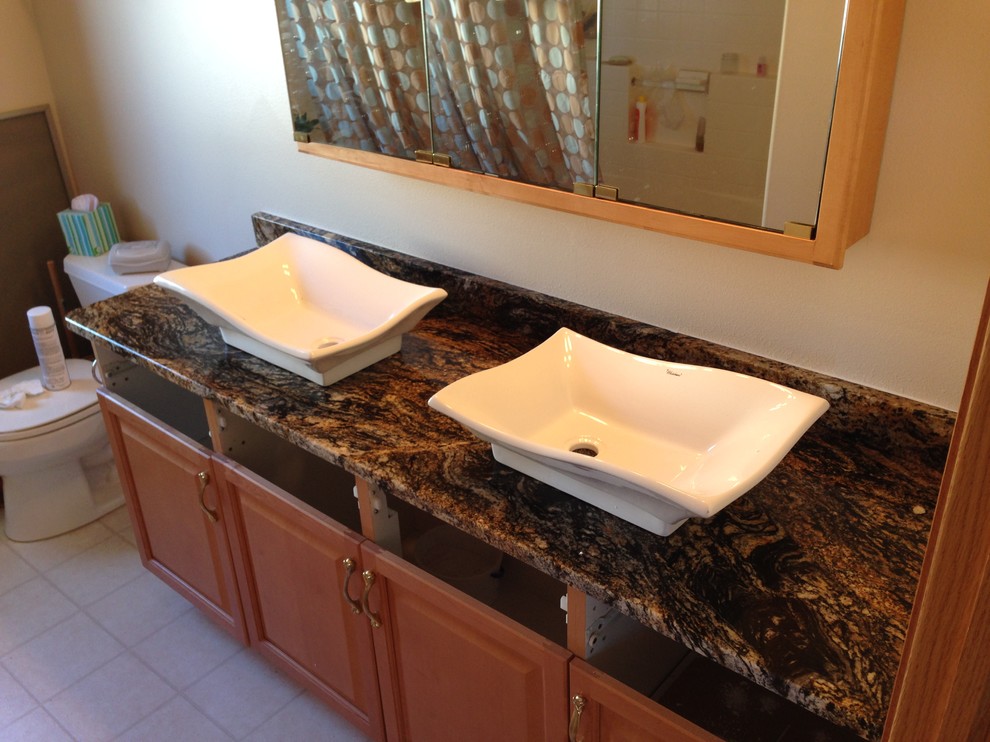 Mid-sized eclectic bathroom photo with a vessel sink, raised-panel cabinets, medium tone wood cabinets and granite countertops