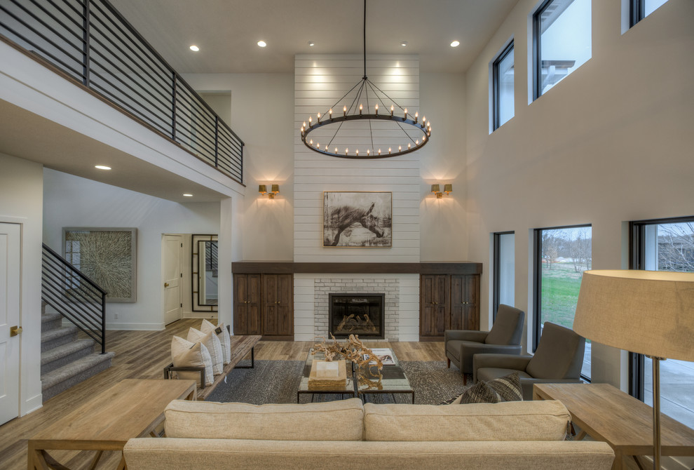 This is an example of a country formal open concept living room in Omaha with white walls, vinyl floors, a brick fireplace surround, beige floor and a standard fireplace.