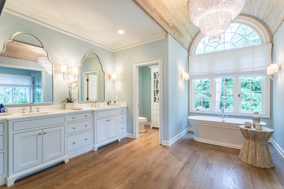 Large transitional master bathroom in Atlanta with shaker cabinets, white cabinets, a freestanding tub, a double shower, a one-piece toilet, gray tile, medium hardwood floors, an undermount sink, a hinged shower door, white benchtops, a double vanity, a built-in vanity and wood.