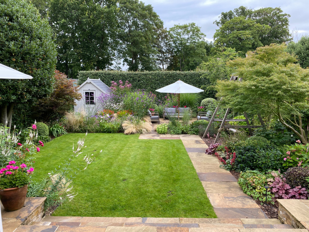 Cette image montre un jardin arrière design de taille moyenne et l'été avec une exposition ensoleillée et des pavés en pierre naturelle.