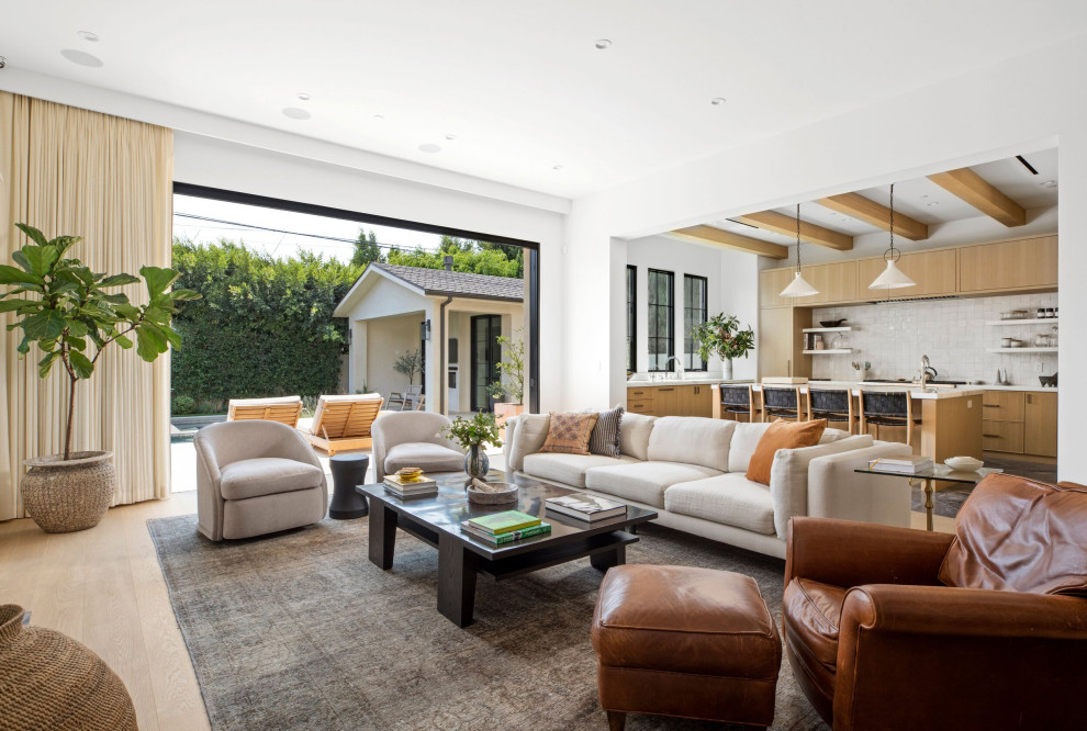 Design ideas for a large transitional open concept family room in Los Angeles with white walls, light hardwood floors, a standard fireplace, a stone fireplace surround, a wall-mounted tv, beige floor and coffered.