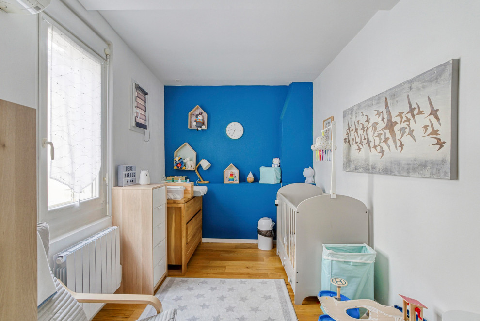 Photo of a mid-sized contemporary kids' room for boys in Montpellier with blue walls, light hardwood floors and brown floor.