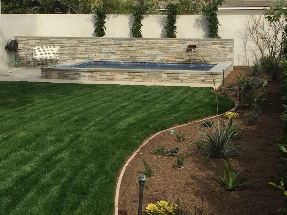 Mid-sized transitional backyard stone and rectangular lap pool fountain photo in Orange County