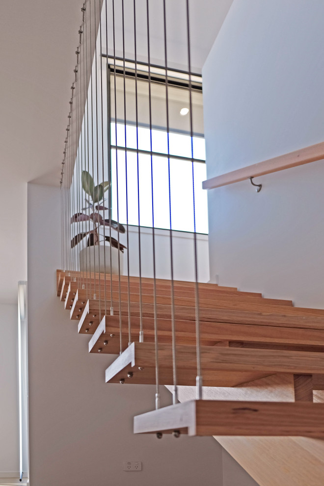 Foto di una piccola scala a rampa dritta minimalista con pedata in legno, nessuna alzata e parapetto in metallo