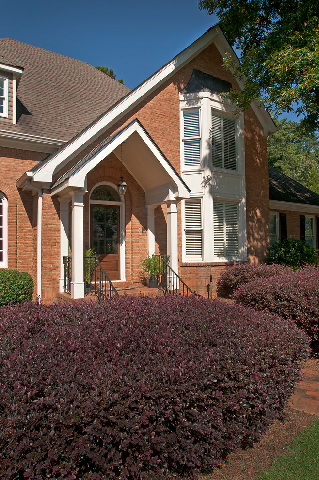 This is an example of a traditional orange house exterior in Atlanta with a gable roof and a shingle roof.