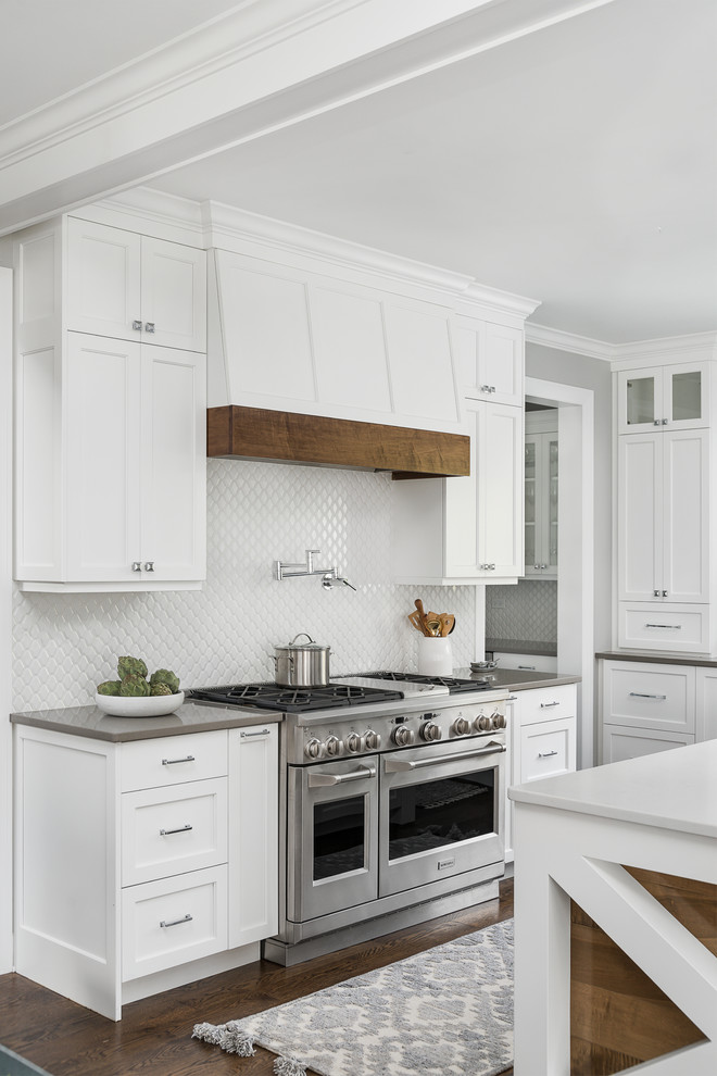 Design ideas for a large beach style eat-in kitchen in Chicago with an undermount sink, beaded inset cabinets, white cabinets, quartz benchtops, white splashback, ceramic splashback, stainless steel appliances, medium hardwood floors, with island, brown floor and white benchtop.