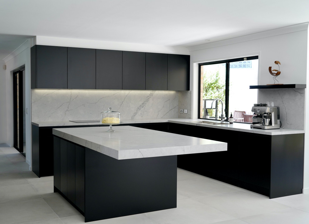 Eat-in kitchen - large modern u-shaped cement tile floor and gray floor eat-in kitchen idea in Sydney with a drop-in sink, flat-panel cabinets, black cabinets, quartz countertops, green backsplash, quartz backsplash, black appliances, an island and gray countertops
