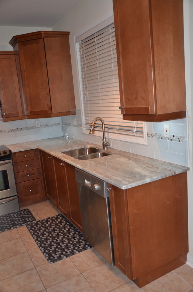 Home design - small transitional u-shaped porcelain tile home design idea in Toronto with a double-bowl sink, beaded inset cabinets, medium tone wood cabinets, granite countertops, white backsplash, glass tile backsplash, stainless steel appliances and no island