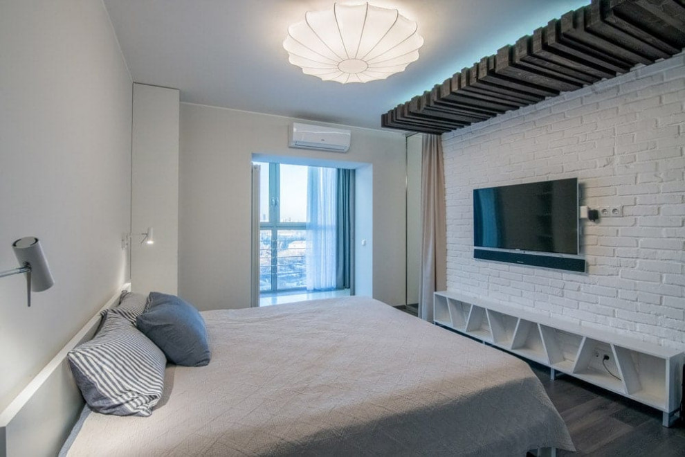На фото: хозяйская, серо-белая спальня среднего размера, в светлых тонах в современном стиле с белыми стенами, паркетным полом среднего тона, серым полом, деревянным потолком и кирпичными стенами без камина