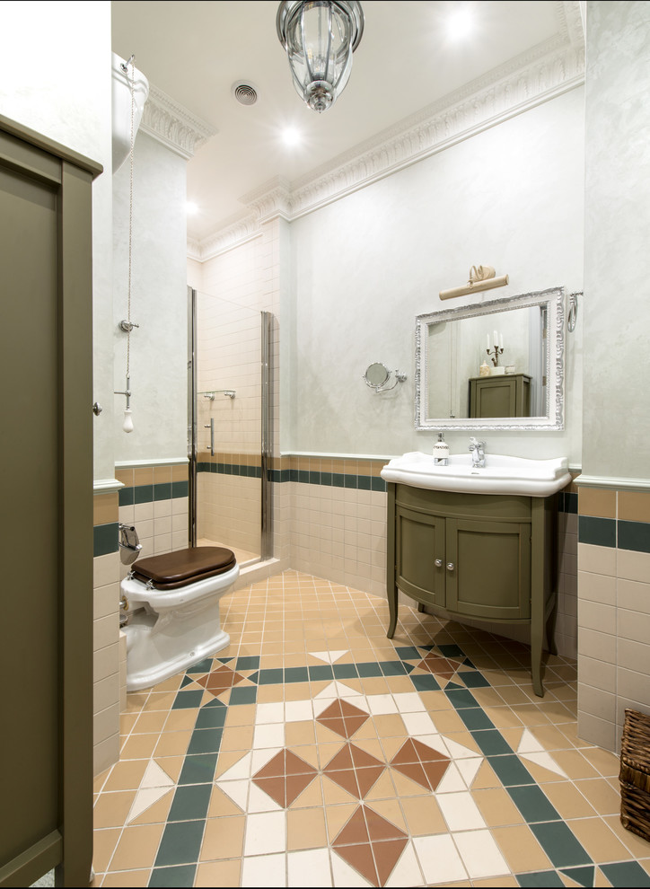 Photo of a small traditional 3/4 bathroom in Moscow with green cabinets, beige tile, ceramic tile, green walls, ceramic floors, recessed-panel cabinets, an alcove shower, a two-piece toilet, an integrated sink, multi-coloured floor and a hinged shower door.