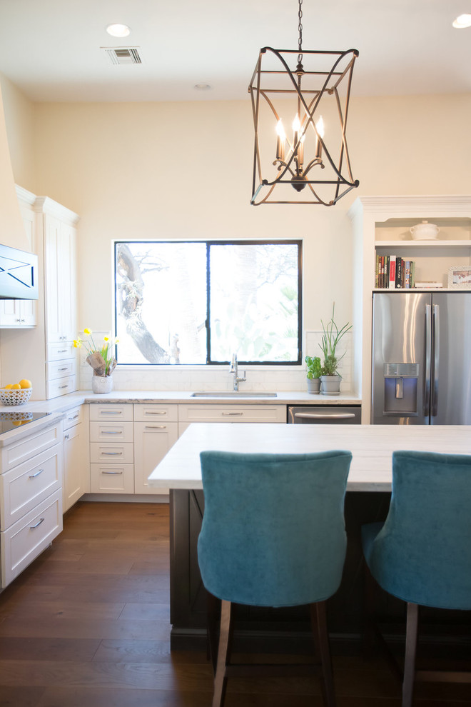 Large transitional l-shaped medium tone wood floor open concept kitchen photo in Phoenix with an undermount sink, shaker cabinets, white cabinets, quartzite countertops, marble backsplash, stainless steel appliances and an island