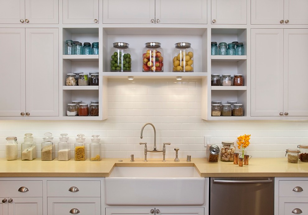 Mid-sized transitional single-wall eat-in kitchen in San Francisco with a farmhouse sink, recessed-panel cabinets, white cabinets, white splashback, subway tile splashback, stainless steel appliances, with island and bamboo floors.