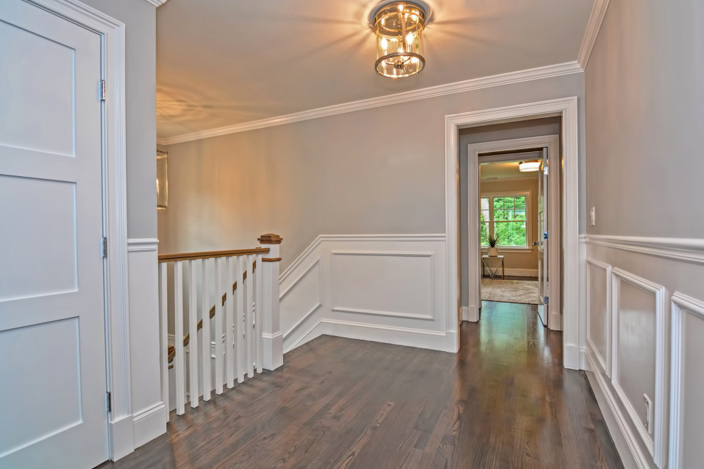 Inspiration pour un couloir traditionnel de taille moyenne avec un mur gris, parquet foncé, un sol gris et du lambris.