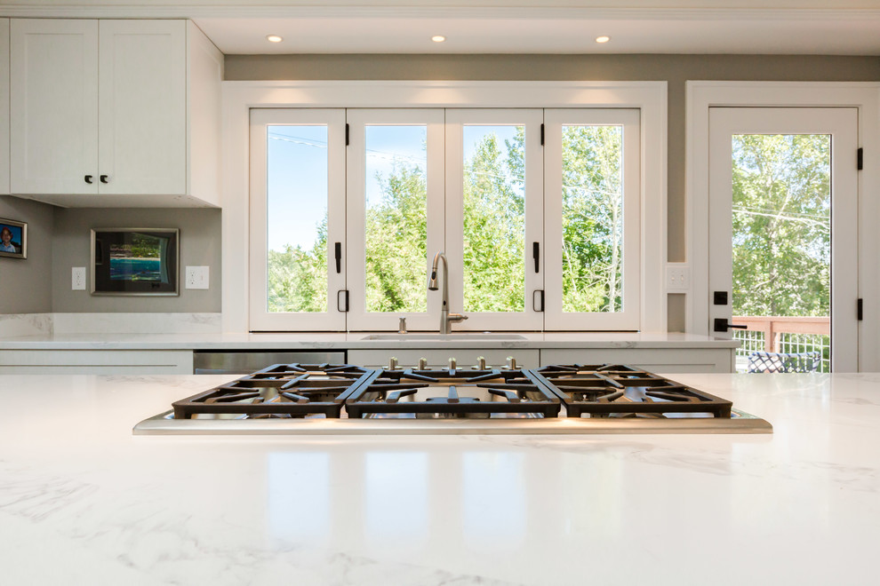 Inspiration for a mid-sized transitional l-shaped dark wood floor and brown floor open concept kitchen remodel in Seattle with an undermount sink, shaker cabinets, white cabinets, quartz countertops, white backsplash, porcelain backsplash, stainless steel appliances and an island