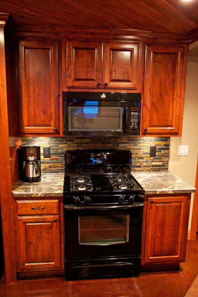Example of a mid-sized l-shaped concrete floor open concept kitchen design with a drop-in sink, raised-panel cabinets, medium tone wood cabinets, laminate countertops, multicolored backsplash, stone tile backsplash and stainless steel appliances