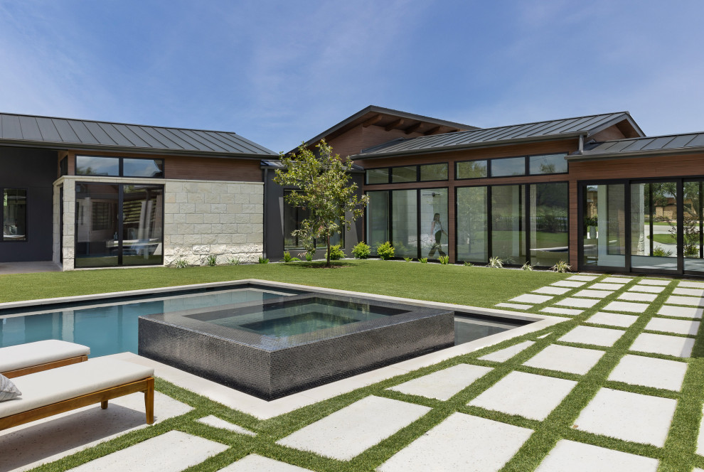 Example of a minimalist backyard concrete paver and l-shaped hot tub design in Austin