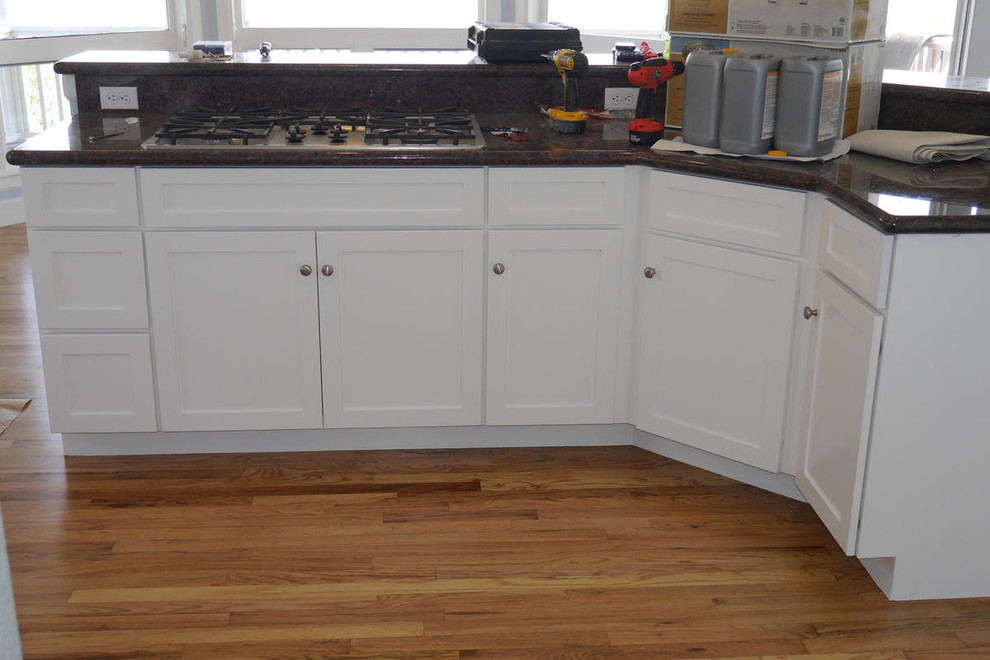 Eat-in kitchen - mid-sized transitional medium tone wood floor eat-in kitchen idea in Denver with shaker cabinets, white cabinets, granite countertops, stainless steel appliances and a peninsula