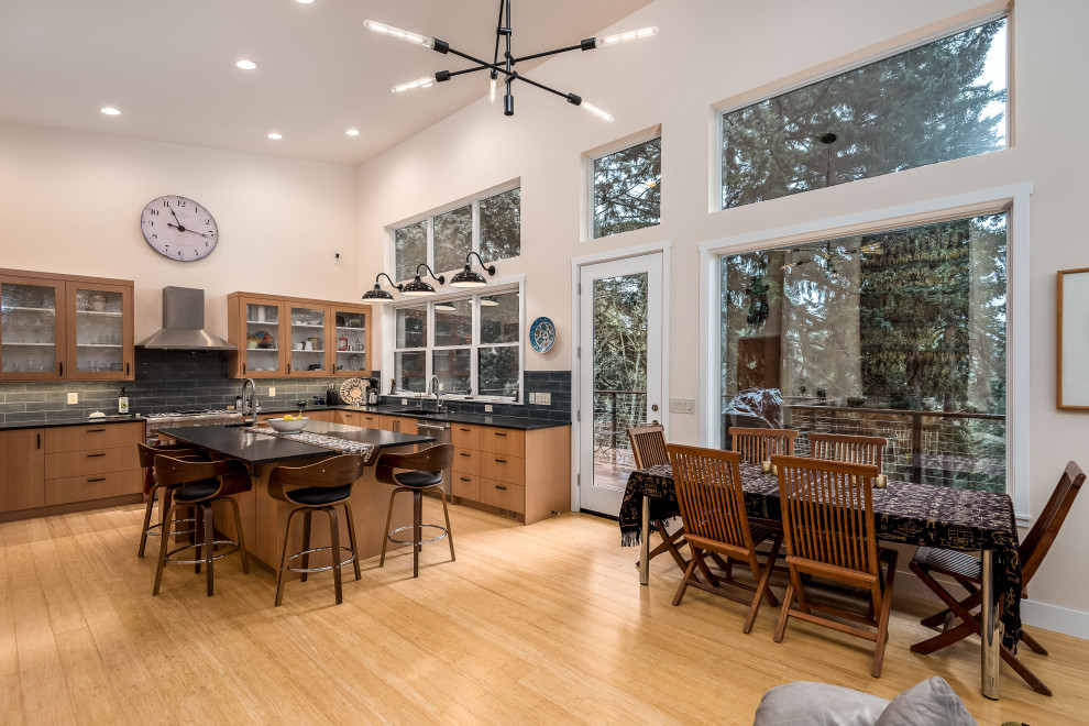 Design ideas for a large midcentury kitchen/dining combo in Portland with white walls, light hardwood floors, a hanging fireplace, a tile fireplace surround and brown floor.