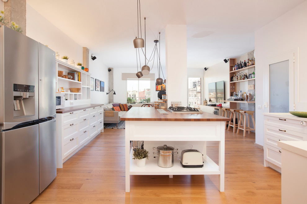 Inspiration for a large scandinavian u-shaped open plan kitchen in Barcelona with recessed-panel cabinets, white cabinets, wood benchtops, with island, brown floor, stainless steel appliances and medium hardwood floors.