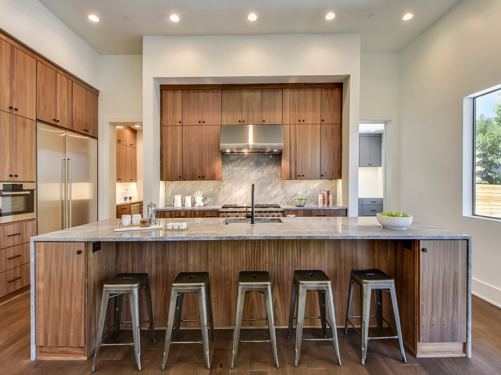 Design ideas for a contemporary kitchen in Austin with an undermount sink, flat-panel cabinets, medium wood cabinets, grey splashback, stone slab splashback, stainless steel appliances, medium hardwood floors, with island and grey benchtop.