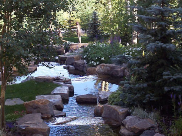 Inspiration for a huge rustic full sun backyard stone water fountain landscape in Denver.